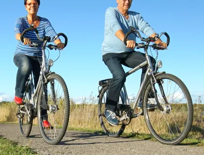 A woman and a man are riding bikes together on a small trail.
